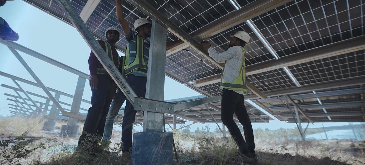 Technicians work on a solar panel in Chattisgarh State, India.