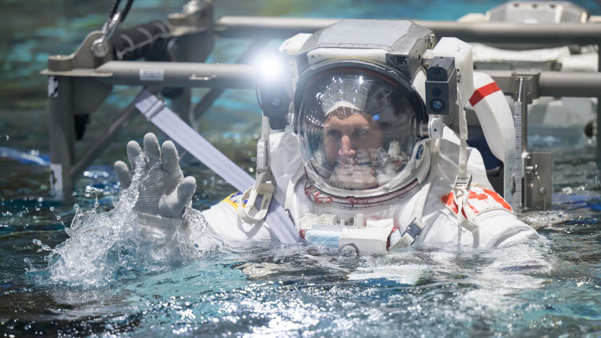 an astronaut in a white spacesuit dives underwater in a pool
