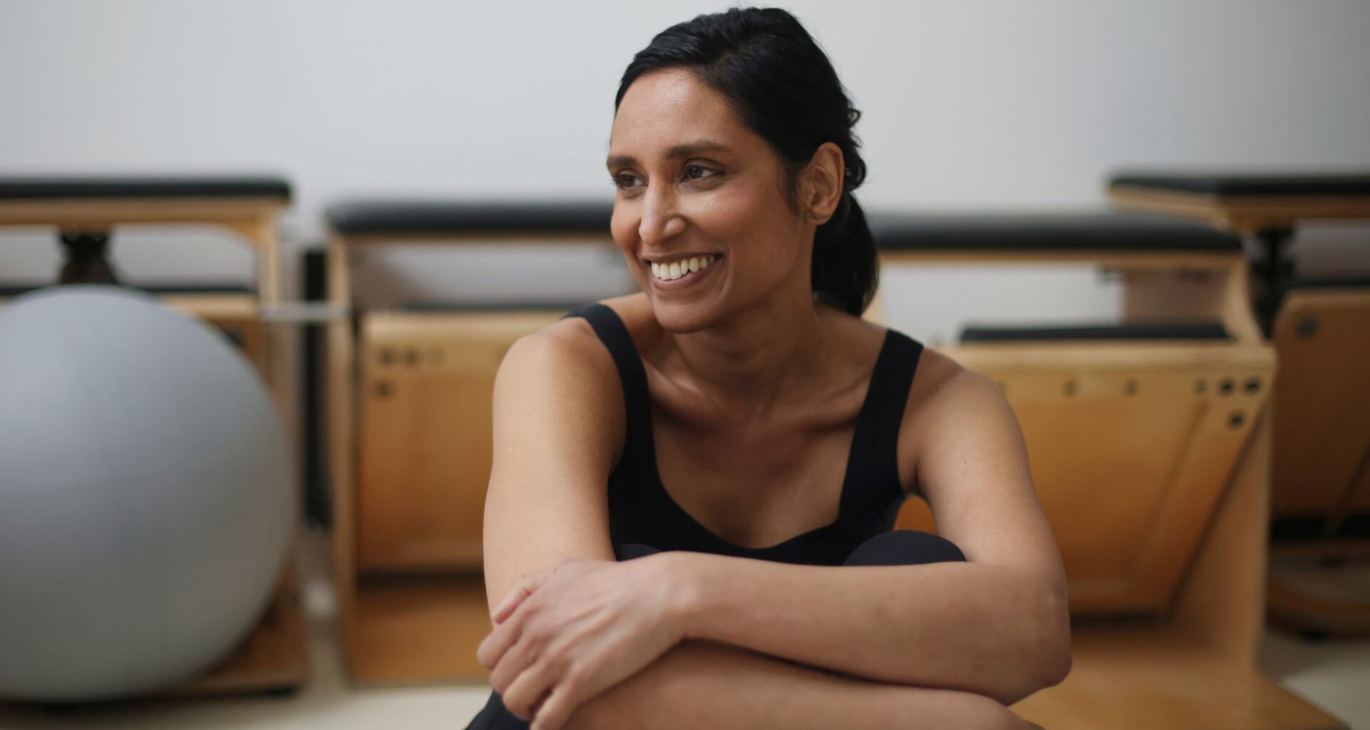 Woman smiling sitting down doing bodyweight Pilates workout