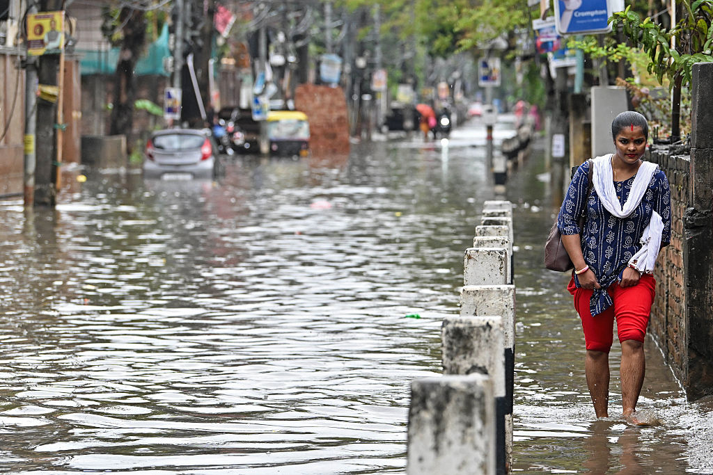 A woman walks on a flooded sidewalk in Guwahati, a city in northeast India.