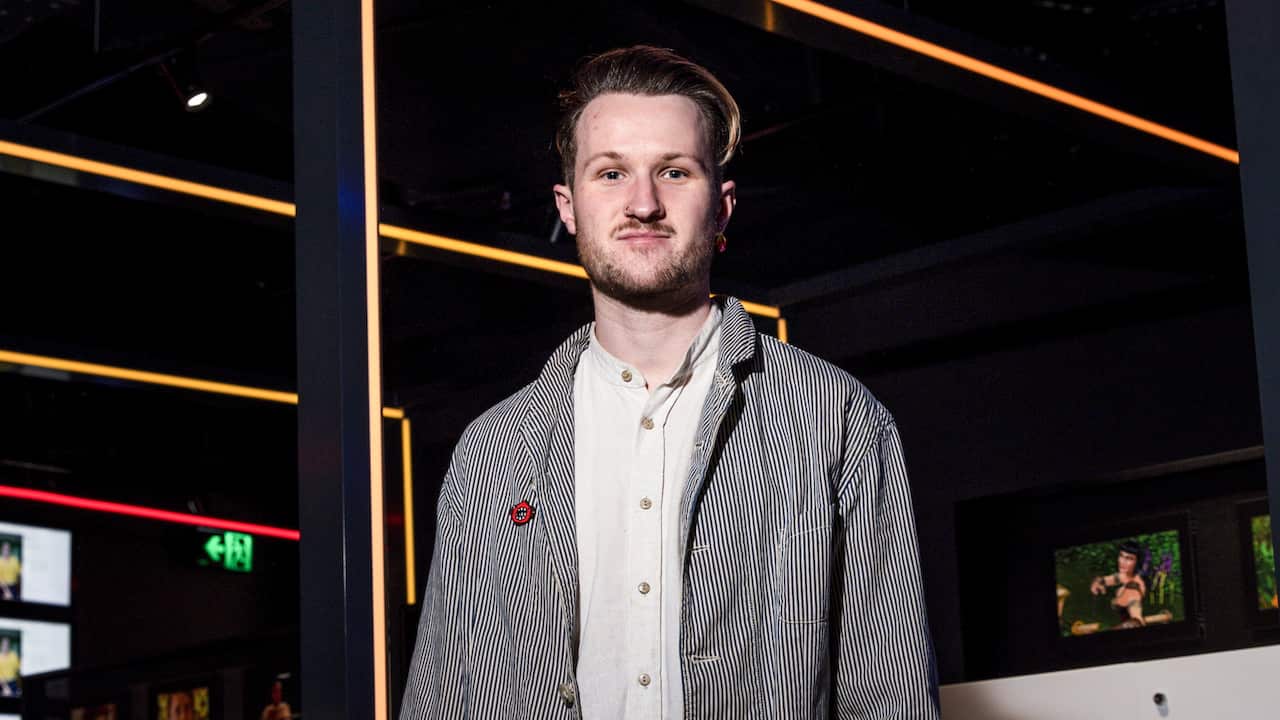 A man wearing a white button-down shirt and pinstripe jacket, smiling and staring at the camera.