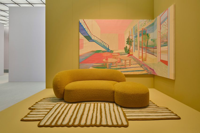 Photo of the Aaland sofa and Pincel rug by Patricia Urquiola and Kartell against a mustard yellow backdrop with a painting of an interior scene behind it