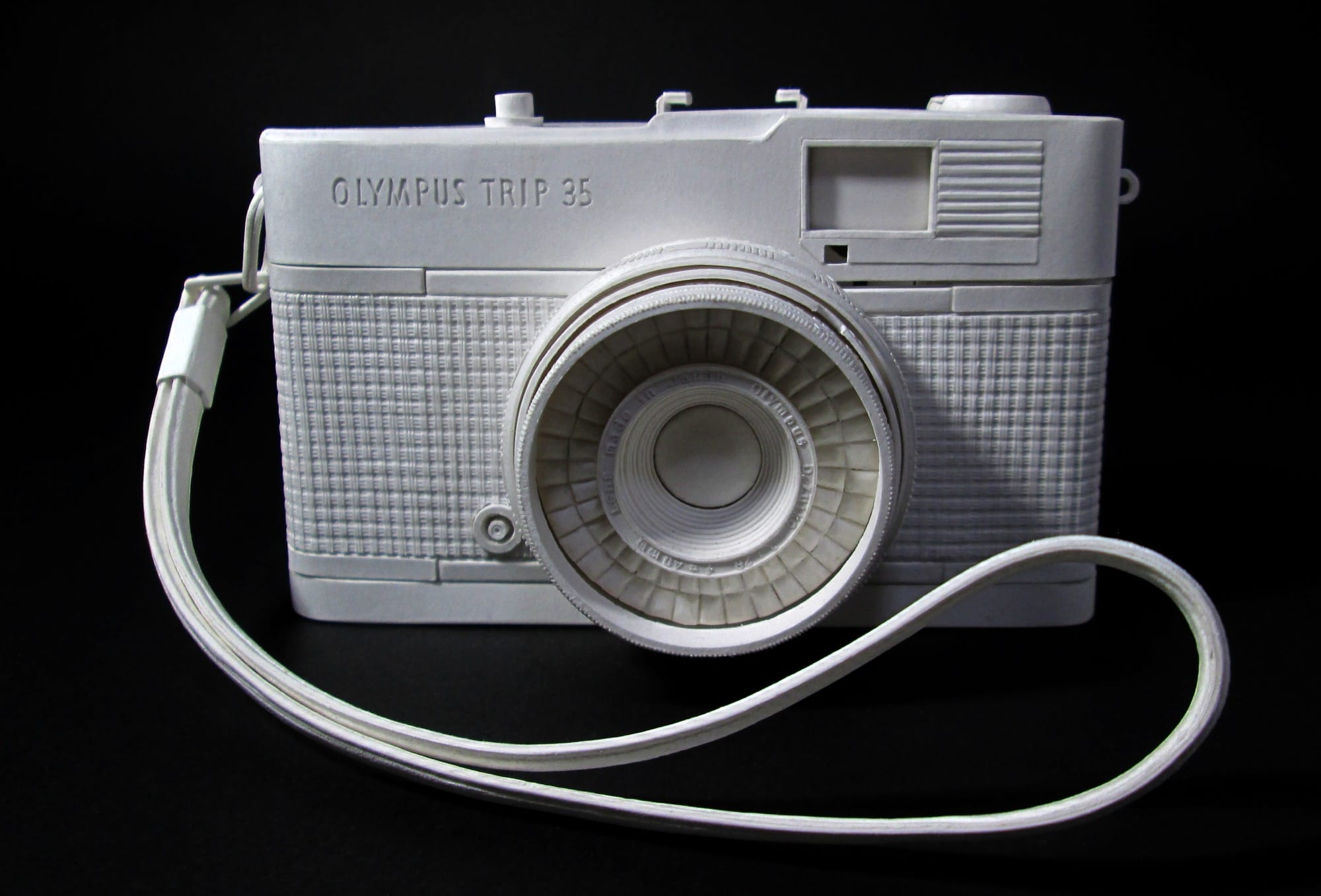 a hyperrealistic, scale sculpture of a 35mm camera made from white paper