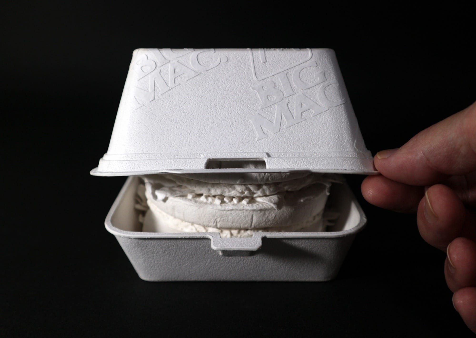a hyperrealistic, scale sculpture of a Big Mac burger and its container made from white paper