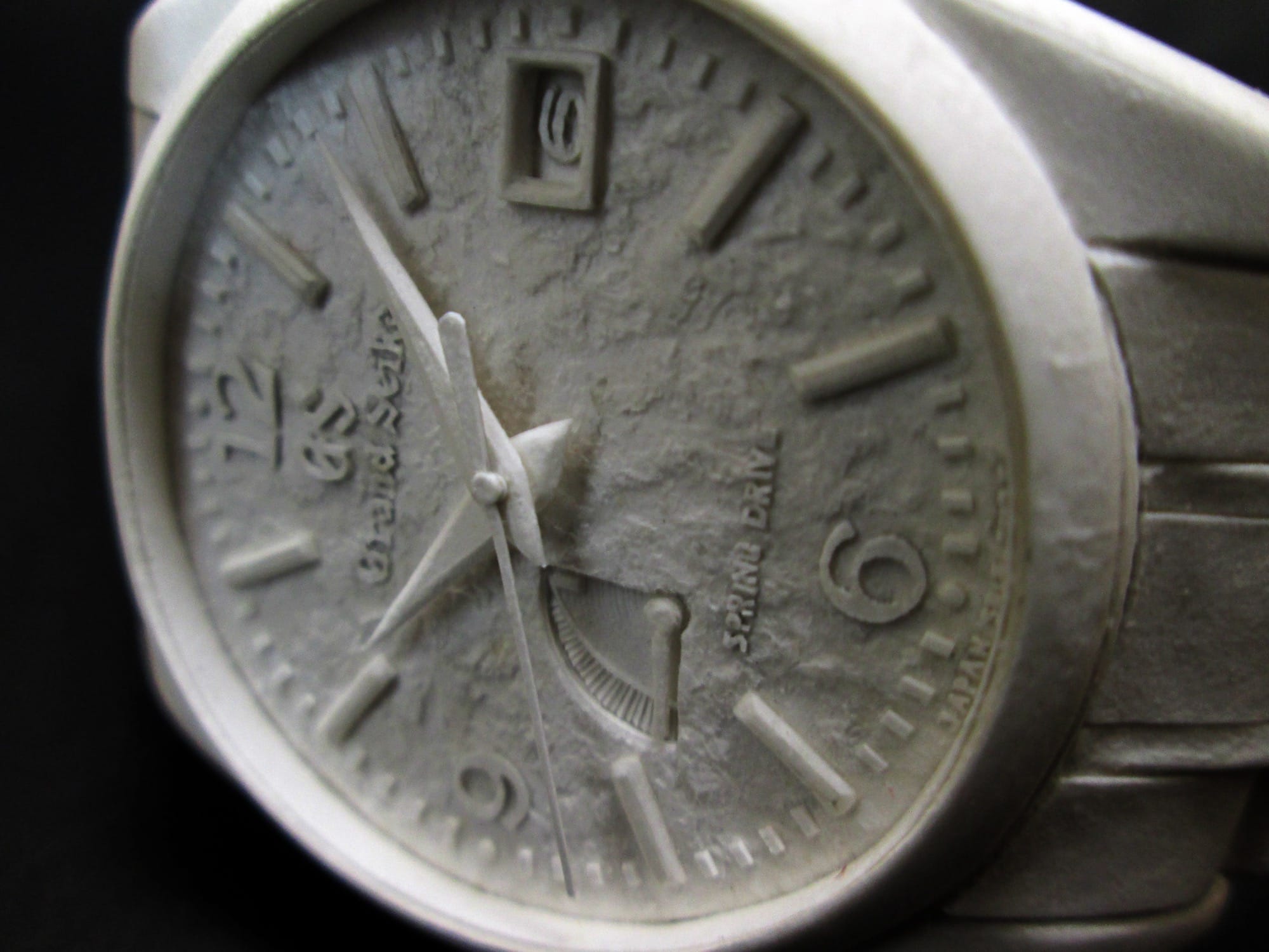 a detail of a hyperrealistic, scale sculpture of a watch made from white paper