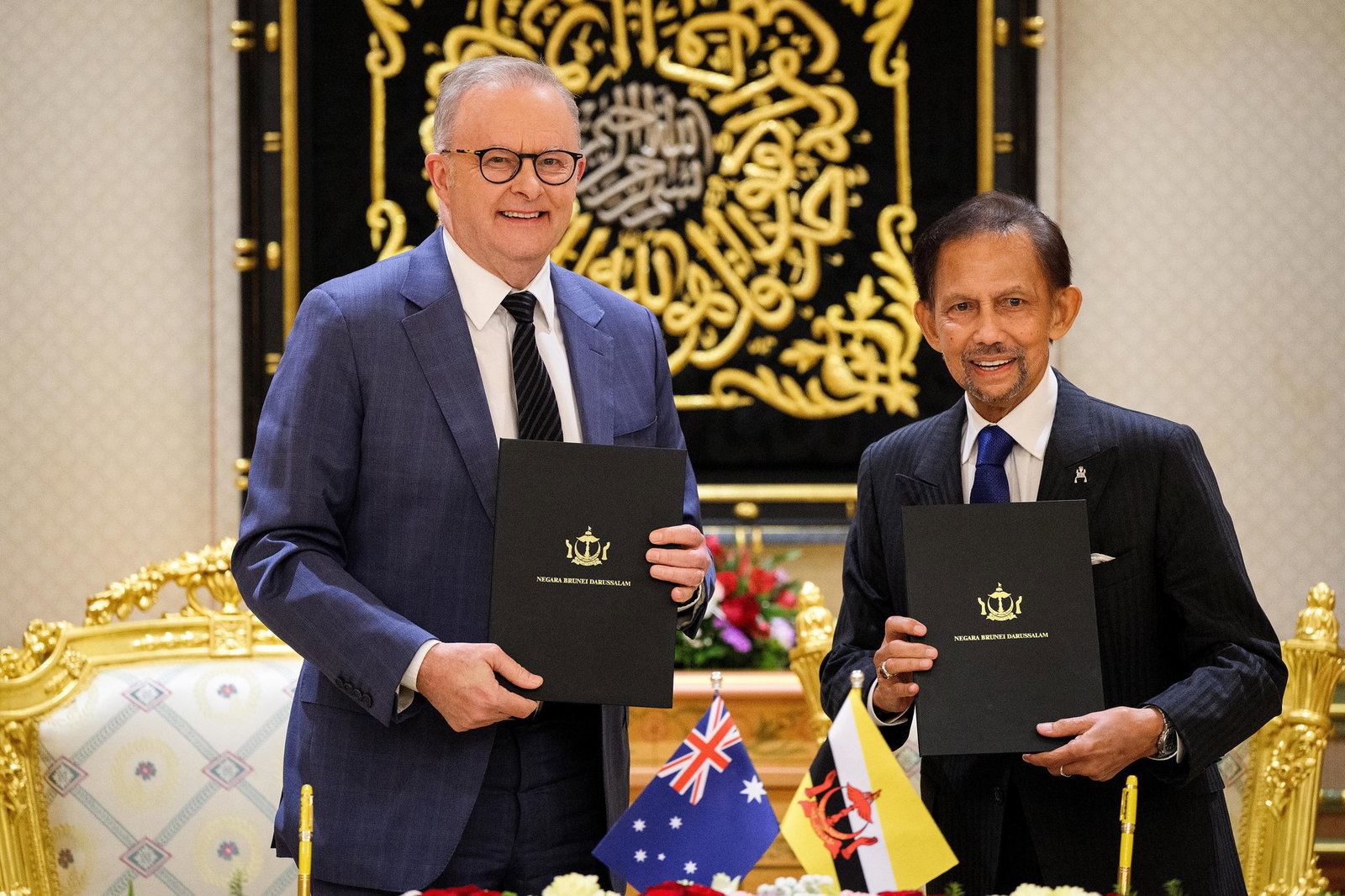 Two men in suits and ties smile while holding an official document