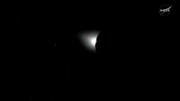 A bright light from the sun peaks out from  behid the moon in the dark of space.