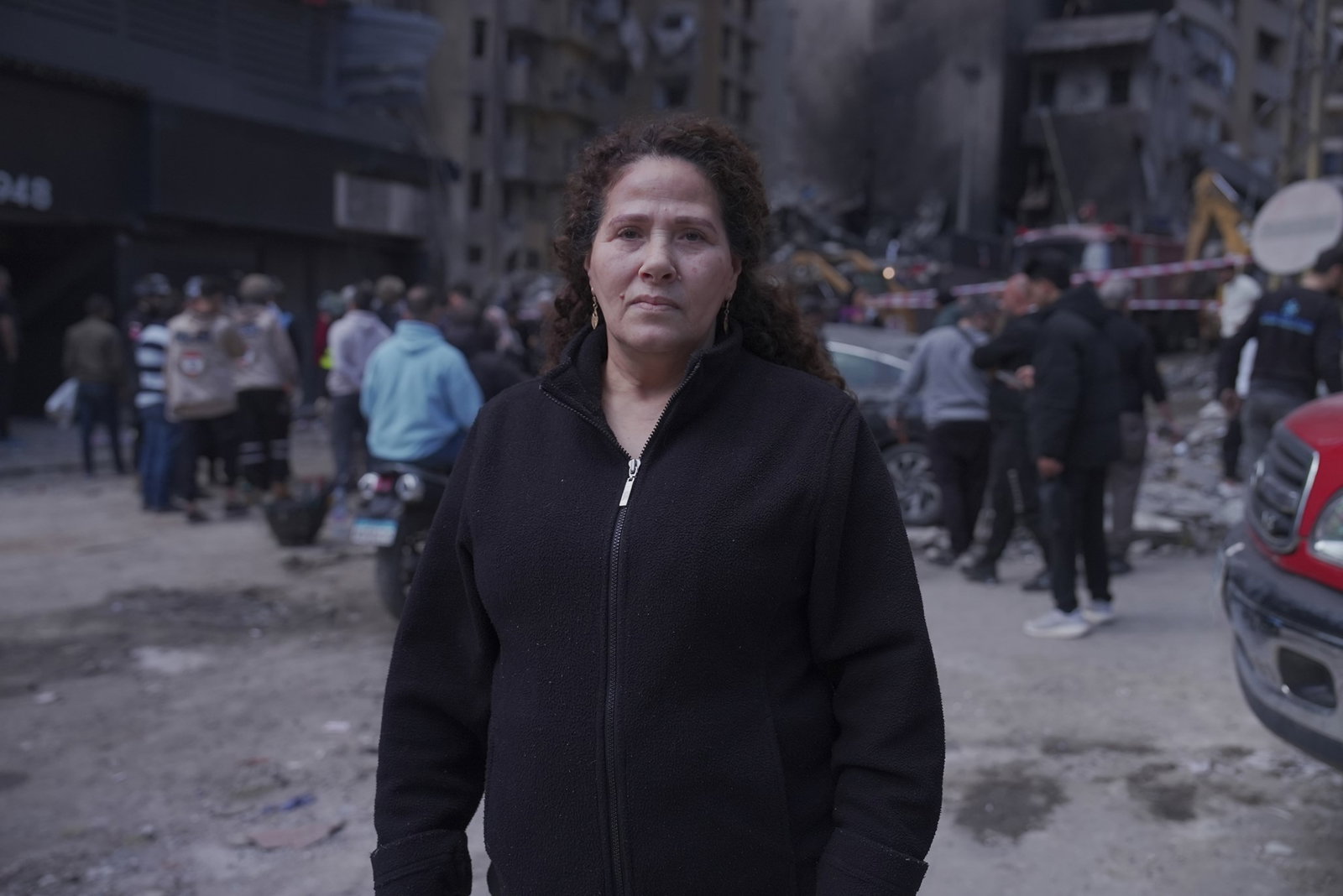 A Lebanese woman Bashia Yehyawi standing in front of a building that has been reduced to rubble
