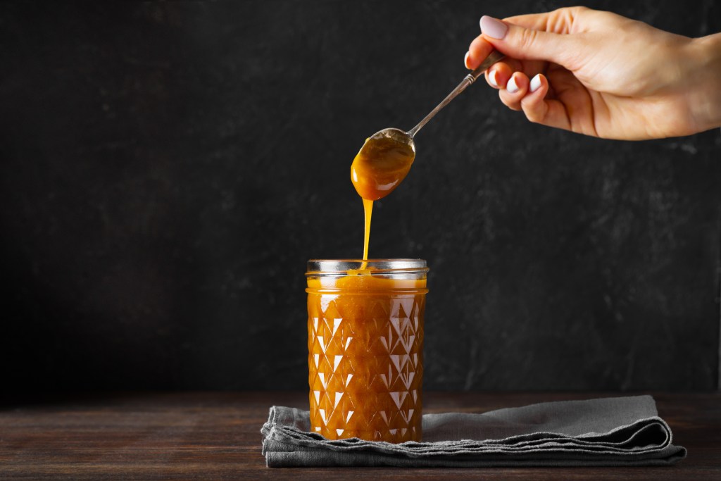 Liquid caramel being drizzled into a glass jar.