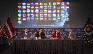Dace Melbārde, Latvia’s Minister for Education and Science, second from right, signs the Artemis Accords, as NASA Administrator Jared Isaacman, second from left, Jacob Helberg, U.S. Under Secretary of State for Economic Affairs, left, and Jānis Beķeris, Chargé D’Affaires a.i. at the Embassy of the Republic of Latvia to the United States, right, look on Monday, April 20, 2026, at the Mary W. Jackson NASA Headquarters building in Washington. The Artemis Accords graphic of all signatory flags is behind them.