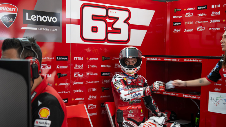 Pecco Bagnaia glances at data in his paddock