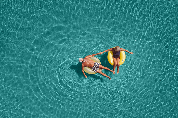Older couple in swimming pool, Getty