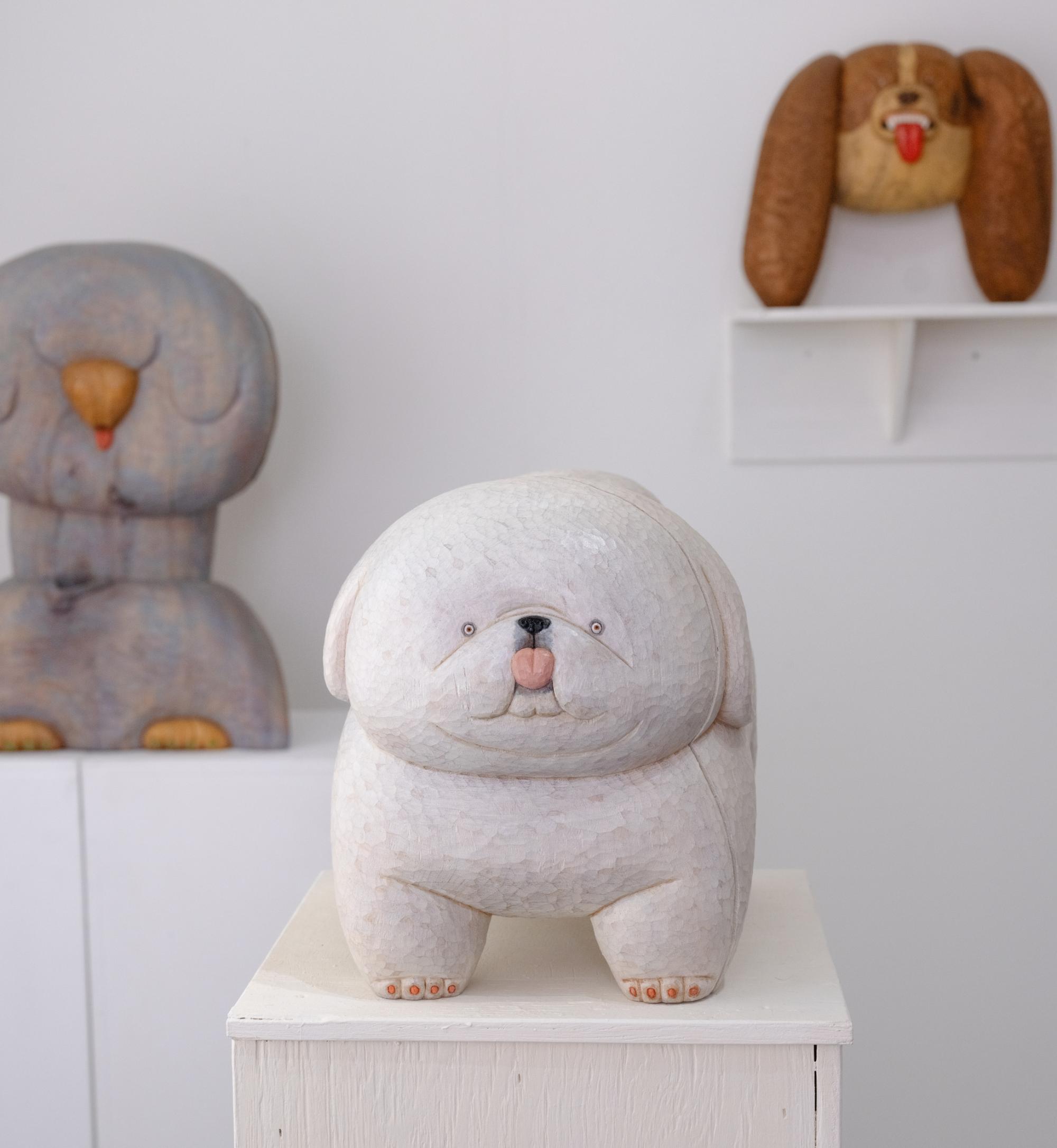 a wood-carved pekingese sculpture by Misato Sano