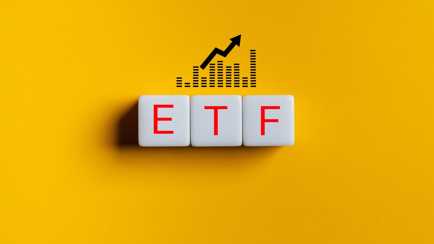 Three white square tiles on a vibrant yellow background spell out the letters 'ETF' in red capital letters. Above the tiles, a black graphic shows a rising bar chart alongside an upward-pointing arrow, symbolizing growth and positive market movement.