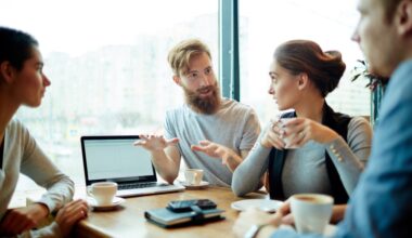 Four people in a relaxed business meeting discussing information on a screen