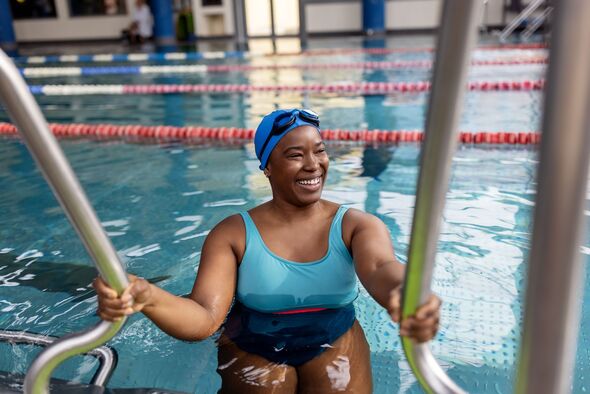 Smiling woman swimmer entering pool