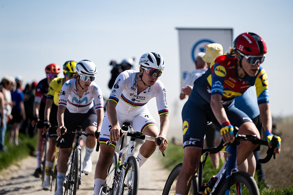 A shot of the peloton competing in Paris-Roubaix Femmes 2025, shot from the front-side. You can see Ellen van Dijk and Lotte Kopecky clearly, with riders blurred in the background