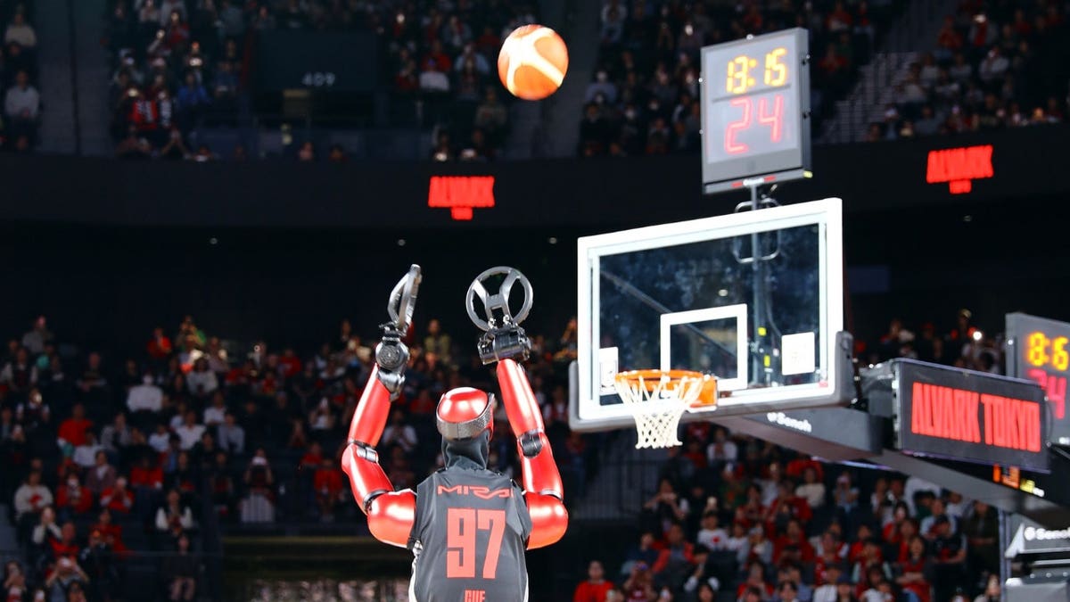 A robot shoots a basketball toward a hoop.