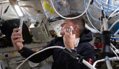 An astronaut sits in capsule surrounded by wires