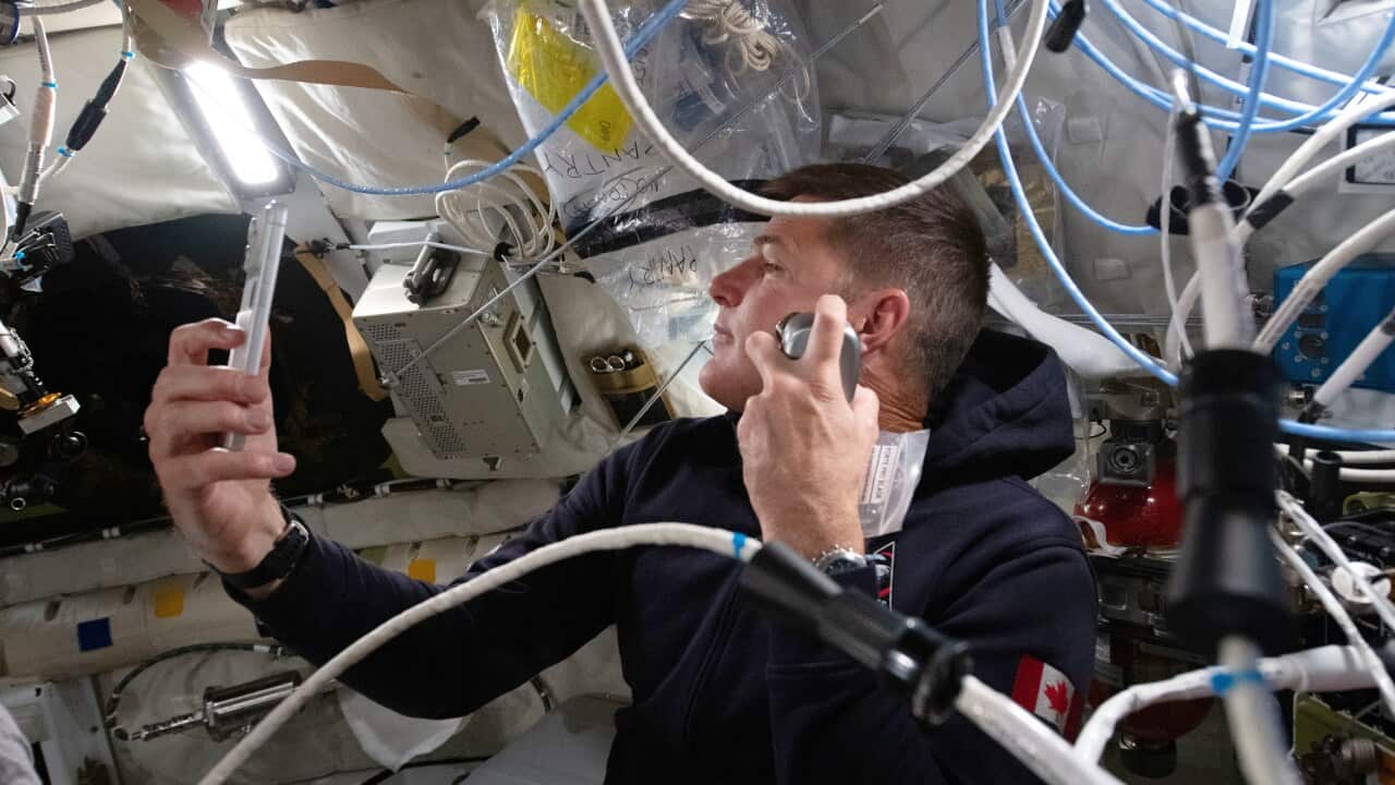 An astronaut sits in capsule surrounded by wires
