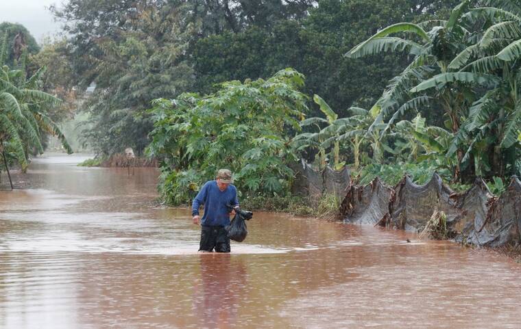 JAMM AQUINO / JAQUINO@STARADVERTISER.COM
A man walks through floodwater on Kaupe Road on March 20, in Waialua. The Hawaii Department of Health and Hawaiian Humane Society are urging residents and recovery workers to monitor for signs of leptospirosis in the aftermath of the Kona low storm floods.