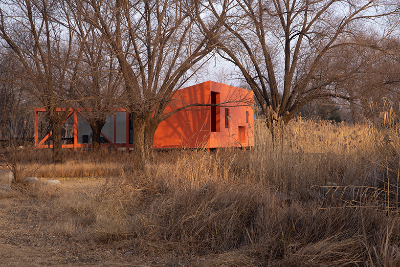 playful crimson timber cabin floats above a stream in chinese cultural park - 2