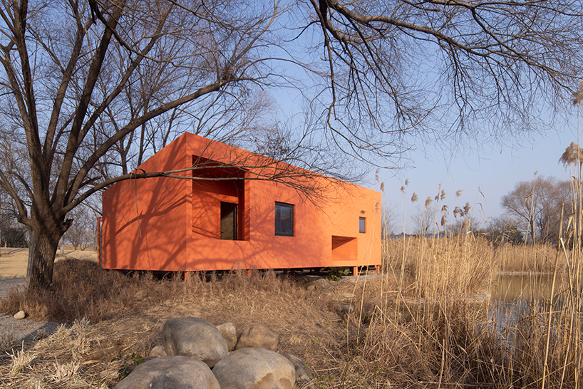 playful crimson timber cabin floats above a stream in chinese cultural park - 1