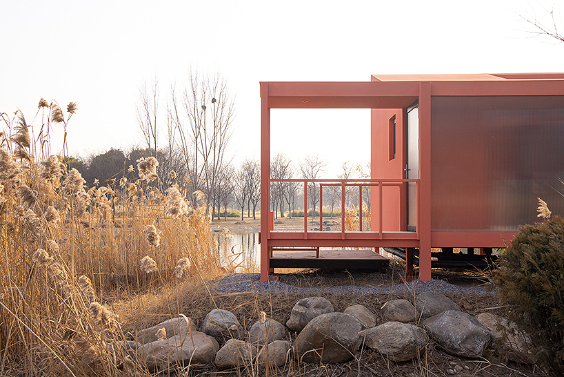 playful crimson timber cabin floats above a stream in chinese cultural park - 3