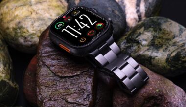 An Apple Watch Ultra 3 with a titanium link-style band lying on wet rocks.