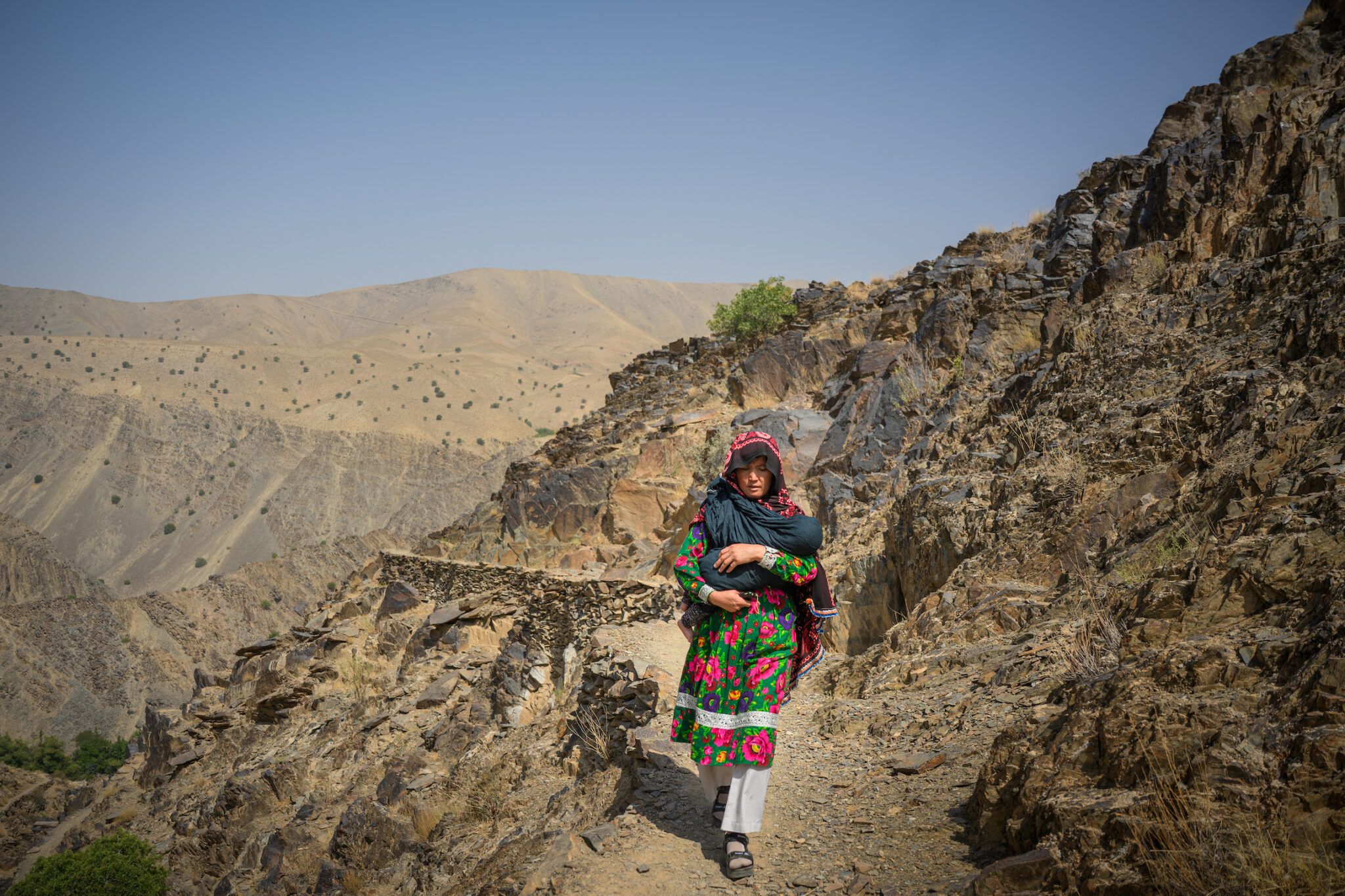Elise Blanchard, “‘I’m Afraid’: Afghan Women Face US Aid Cuts,” for TIME. Zahira walks back from visiting a pregnant woman who is worried she might have to give birth without a midwife. Dahan-e-Tokhomak, Miramor district, Daikundi province, Afghanistan, July 24, 2025.