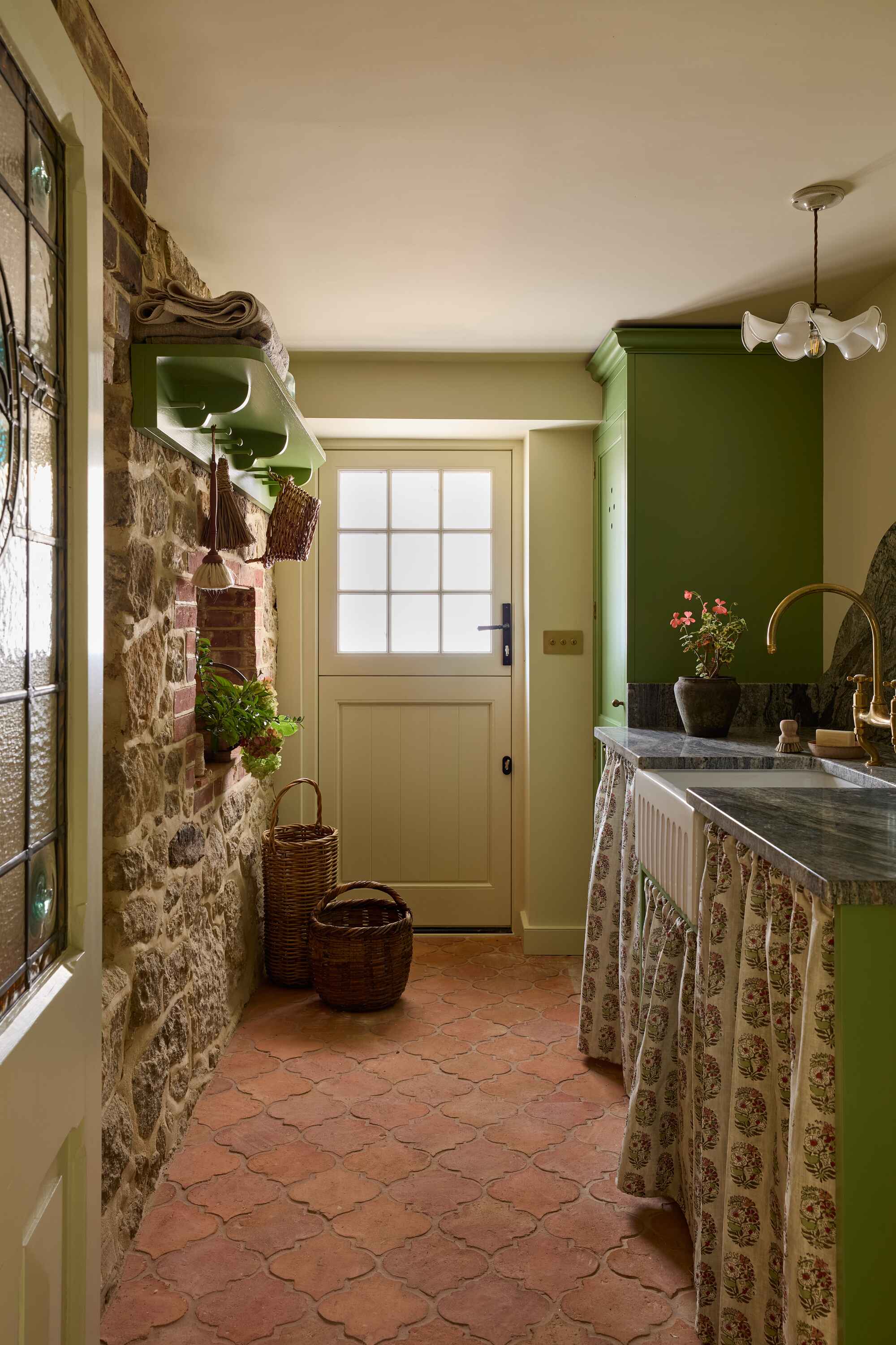 a farmhouse laundry with cabinet skirts and a stone wall