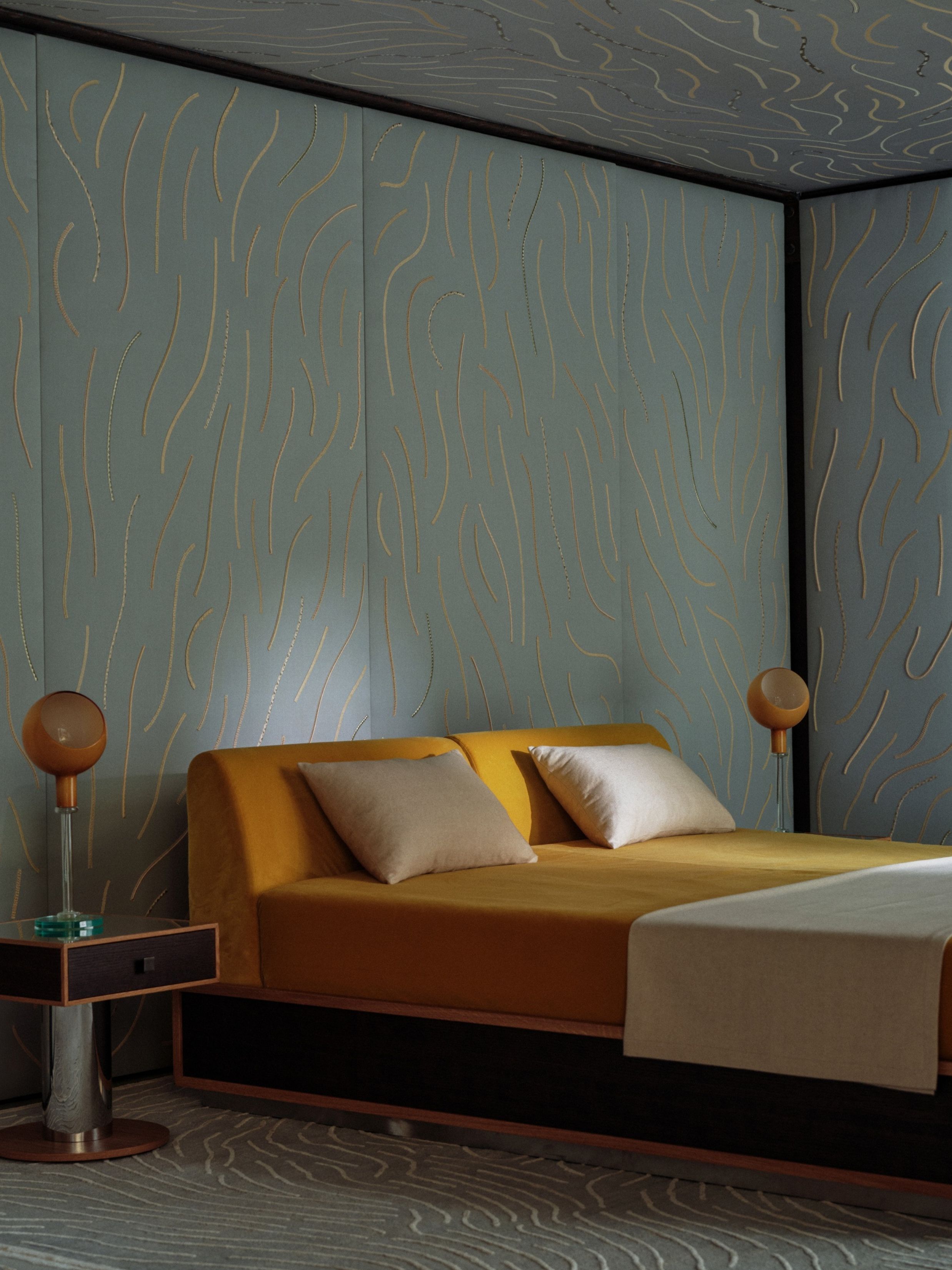 a bedroom with a blue patterned wall and yellow bed