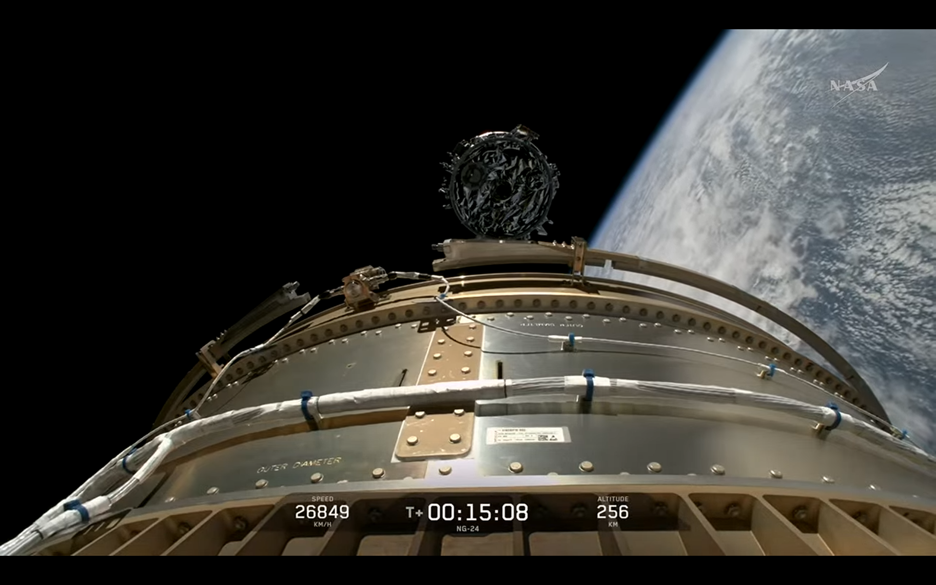 A huge cylindrical NG-24 spacecraft separates from its SpaceX rocket high above Earth.