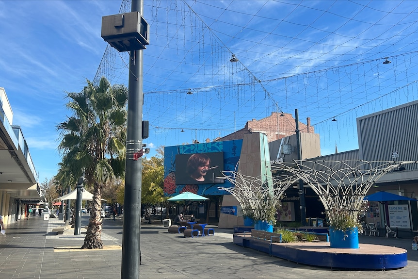 A shopping mall shows a single person walking along empty shops