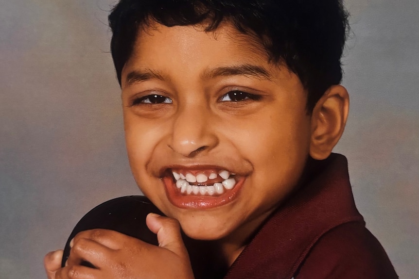A young boy smiles widely at the camera.