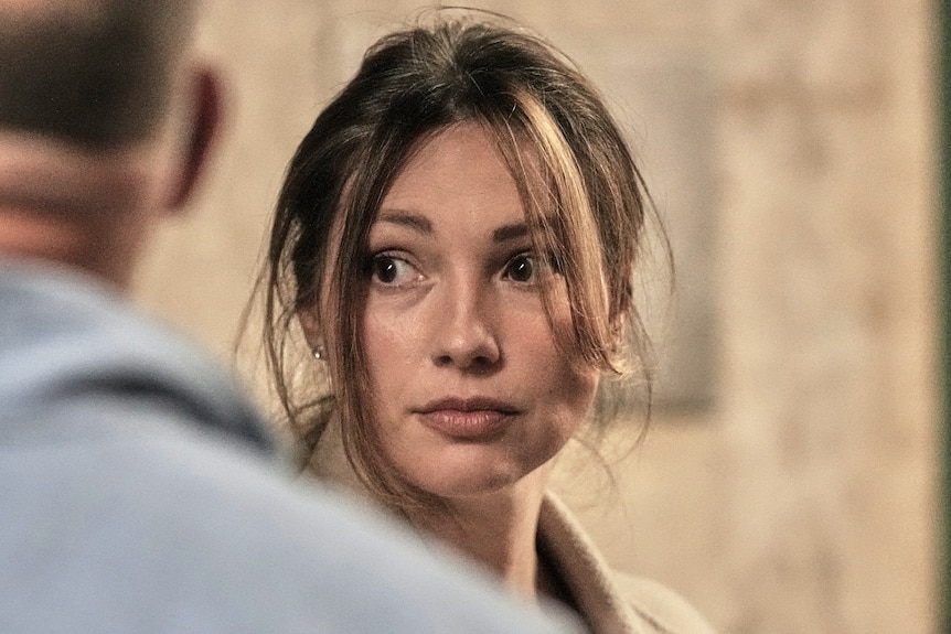 A woman turns with messy hair.