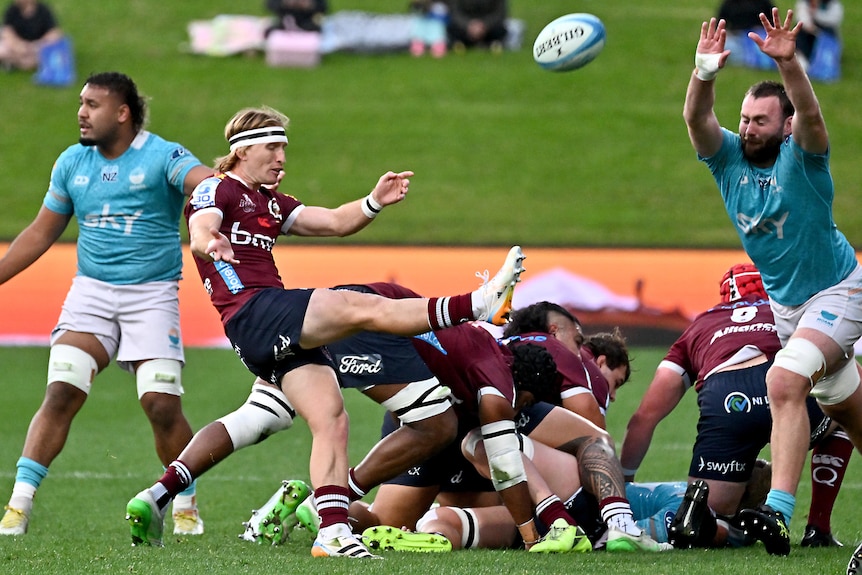 Tate McDermott does a box kick for the Queensland reds against Moana Pasifika.