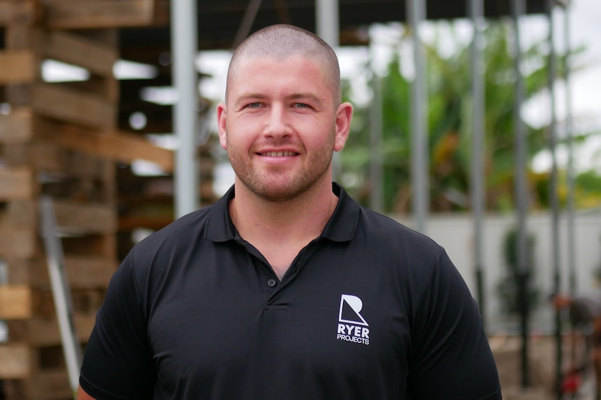 man smiling with construction site in background