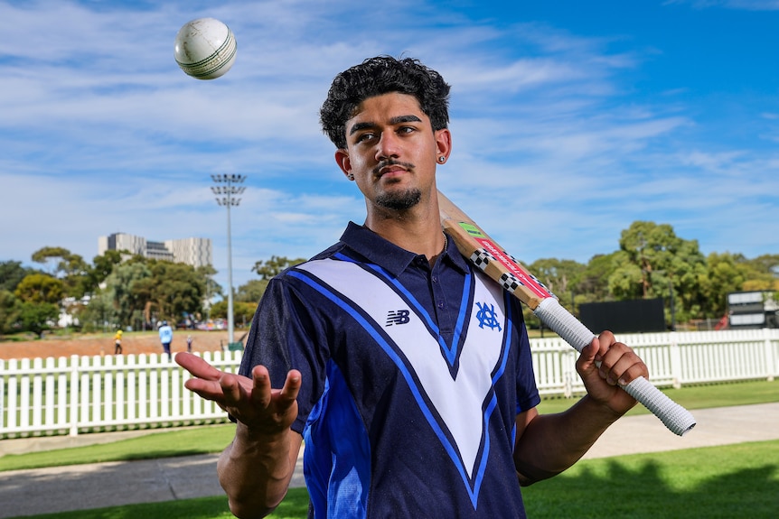 Simrth Gill tosses up a cricket ball, while holding a cricket bat.