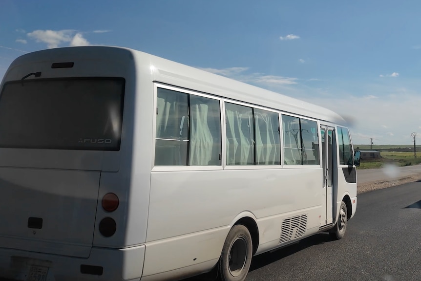 A bus driving down a road in the middle of a flat plain.