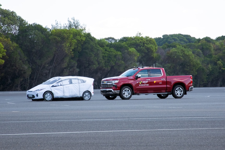 Two cars on a roadway, one a passenger car, the other a large ute