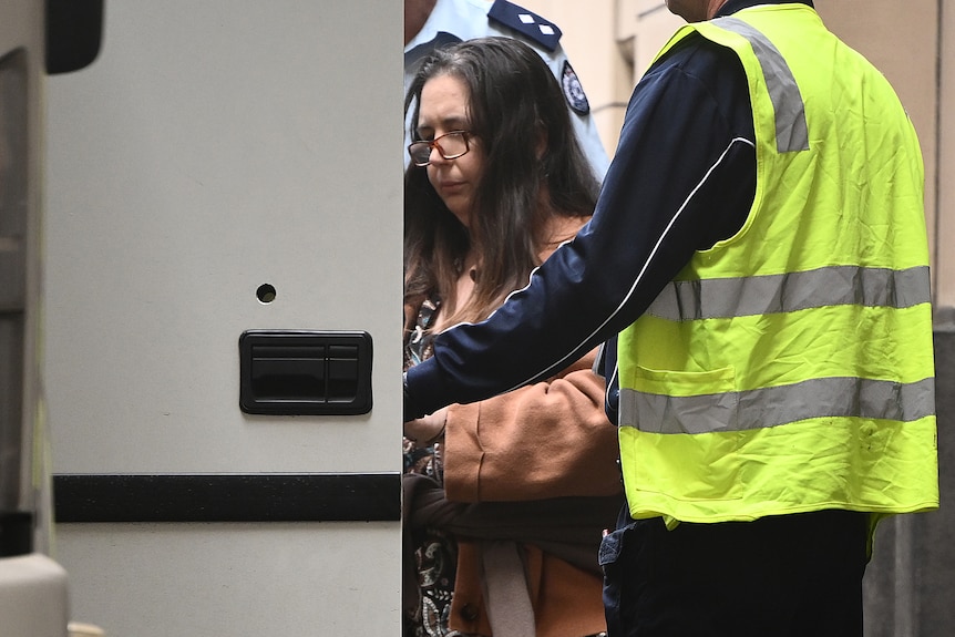 Erin Patterson with glasses on and head down gets into a van outside court