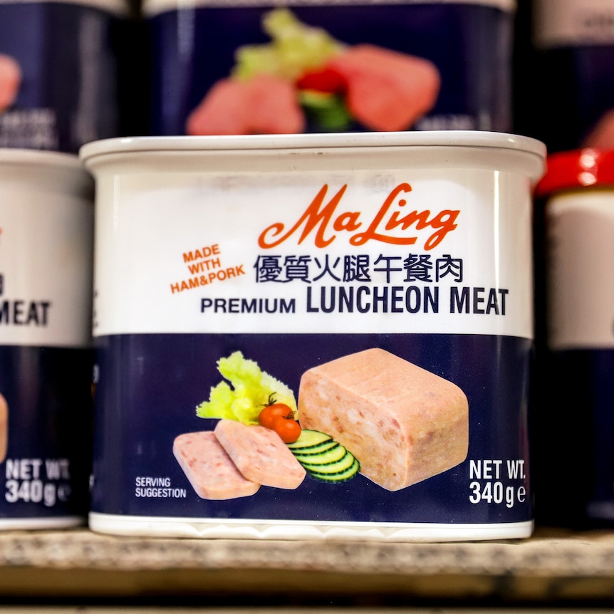 Cans of luncheon meat displayed on a supermarket shelf