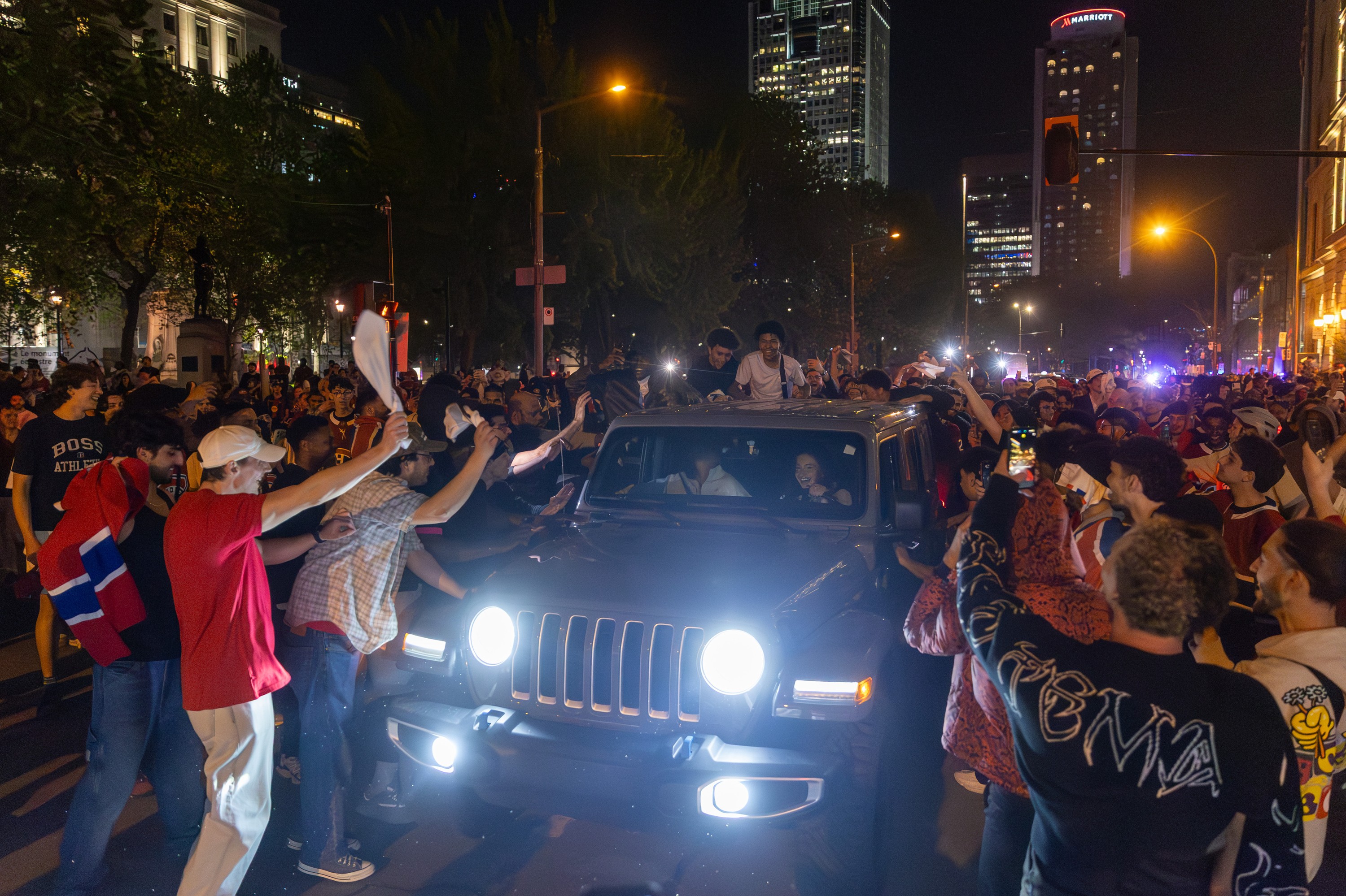 Canadiens fans surround a jeep on a street at night