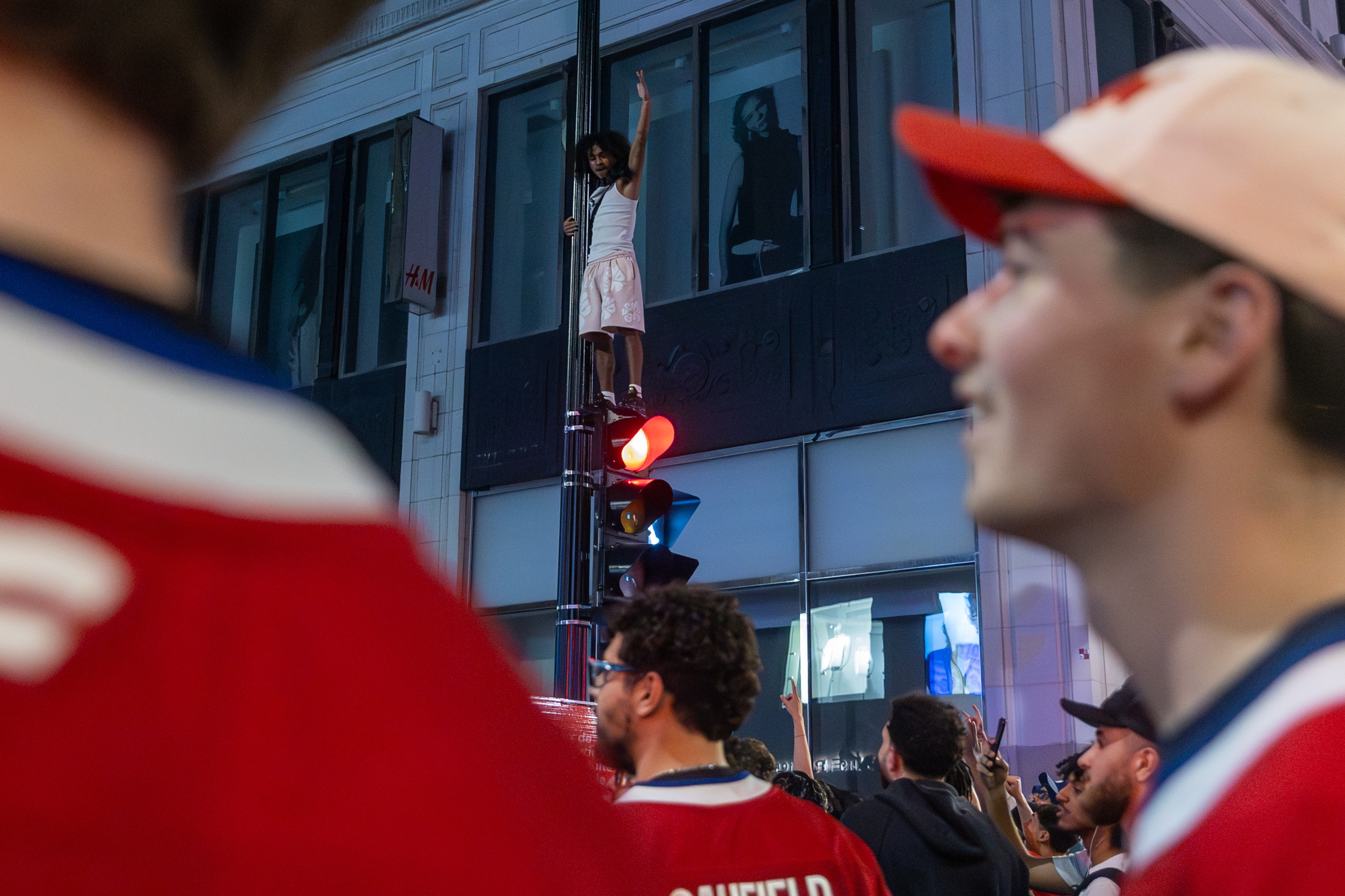 A fan celebrates on top of a street light 