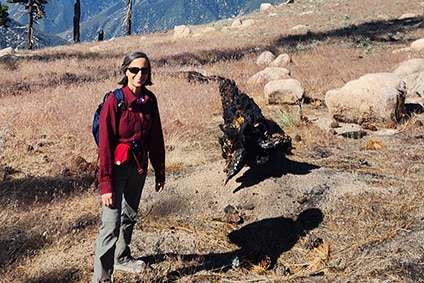 A woman in a red jumper stands on a hiking trail in California.