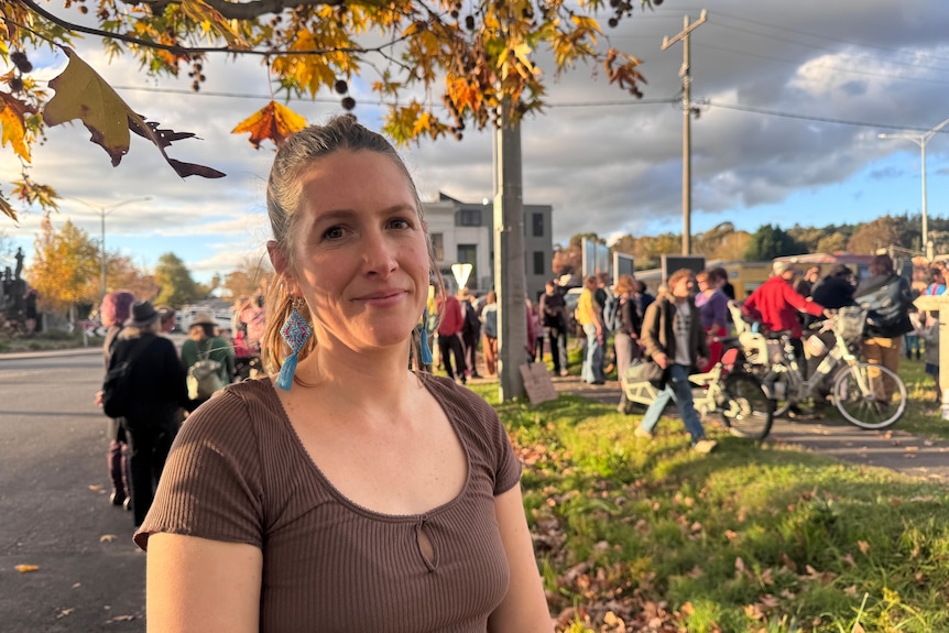 A woman wearing a brown top standing near a protest.
