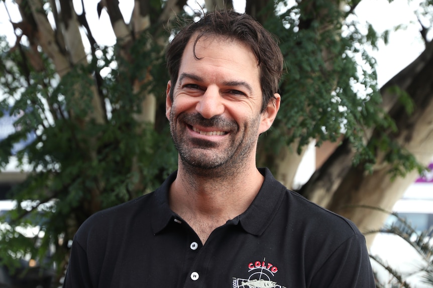 Headshot of white man with dark hair smiling.