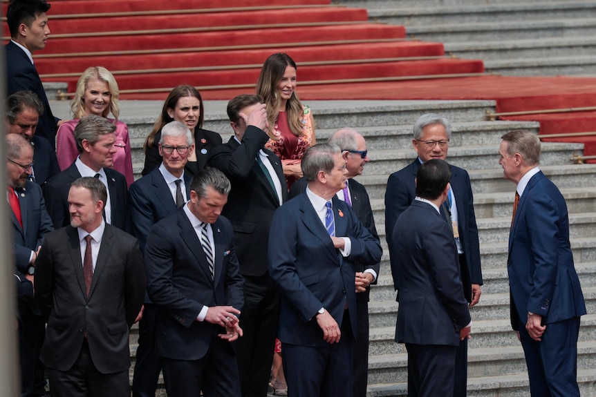 A group of people stand on red steps.