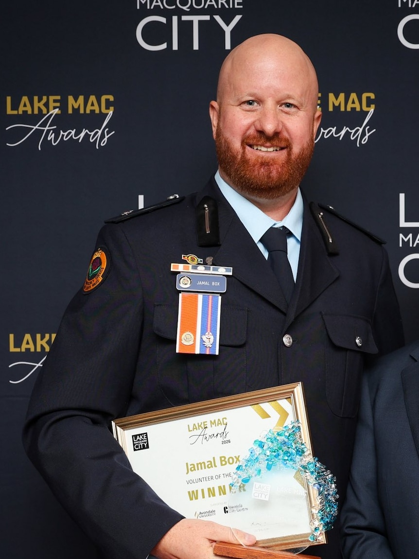 Man in suit hold an award.